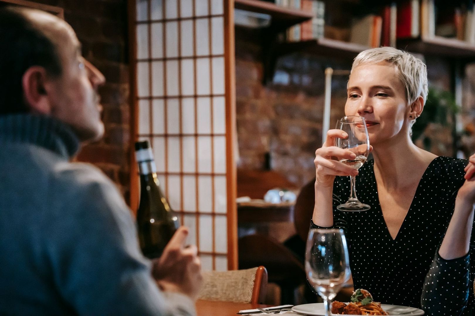 Two diners converse over drinks in a busy restaurant setting