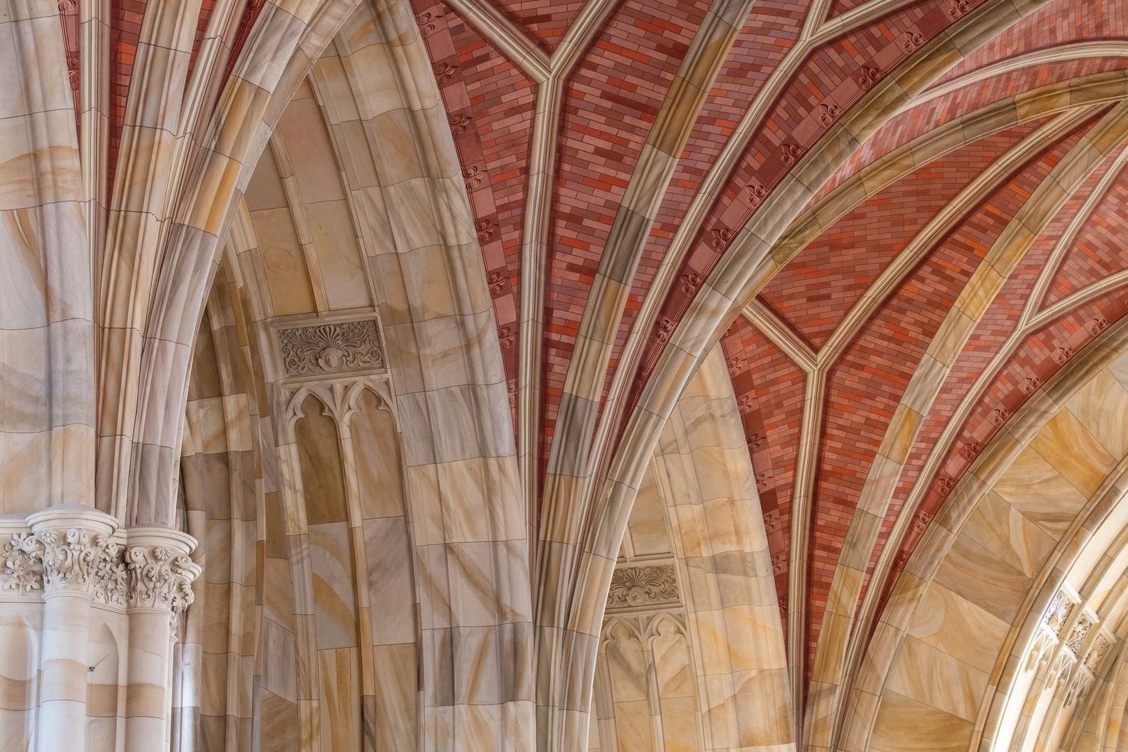 Gothic stone arches and red-brick ribbed vaulting inside a historic building