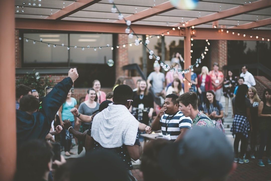 Crowd gathered at a lively outdoor party beneath strings of lights